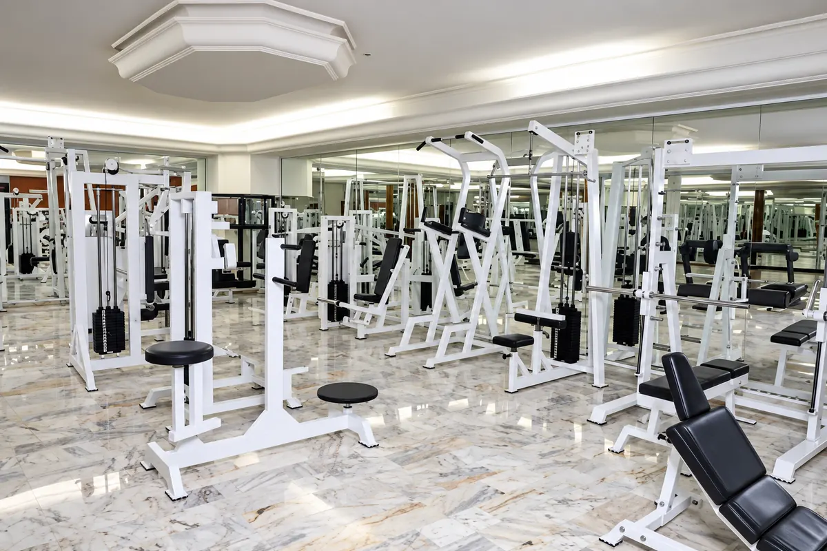 La salle de Viccini Club : appareils de musculation blancs sur sol en marbre